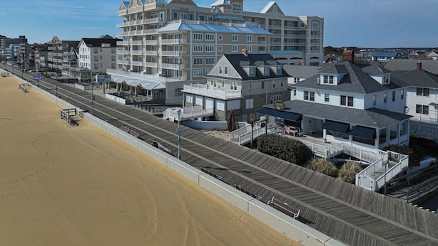 A beachfront hotel with multiple balconies, a boardwalk, and a sandy beach. - Spacious Group Retreat Steps to Beach (Ocean City)