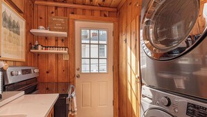 A compact laundry room with wooden walls, a white door, and a stainless steel washer and dryer. - Spacious Group Retreat Steps to Beach (Ocean City)