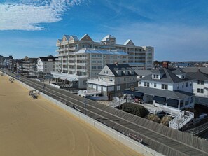 Ein Strandhotel mit mehreren Balkonen, einer Promenade und einem Sandstrand.