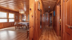 Un interior de madera con zona de comedor, una araña y un pasillo que conduce a otras habitaciones.