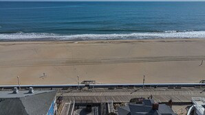 Vista a la playa con un paseo marítimo de madera y un edificio de techo plano.