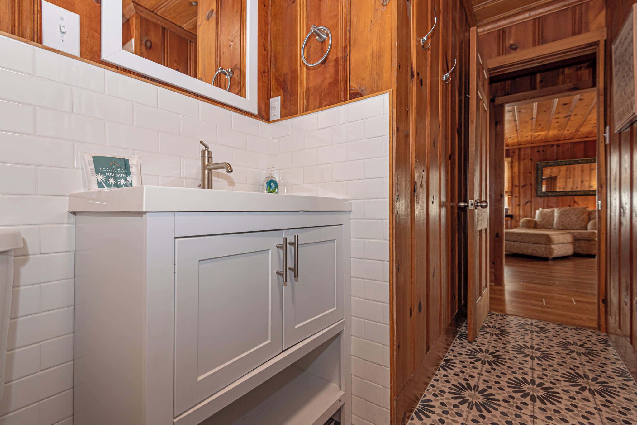 Une salle de bain avec un lavabo blanc, des meubles en bois et un sol carrelé.