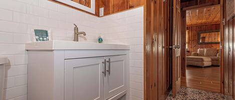 Une salle de bain avec un lavabo blanc, des meubles en bois et un sol carrelé.