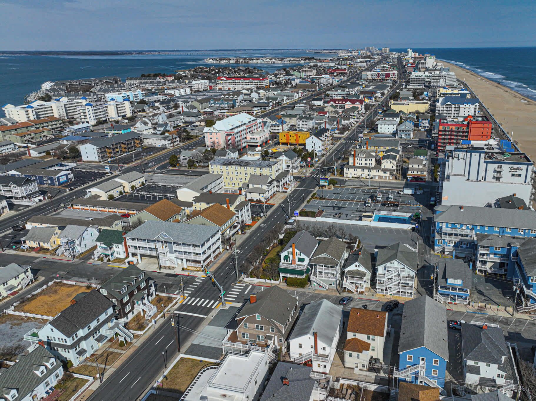 Vue aérienne d’une ville côtière, avec une longue plage, des immeubles résidentiels denses et un mélange de commerces.