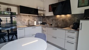 A modern kitchen with a round dining table, white cabinets, and a built-in stove. - Nice little apartment (Pornic)