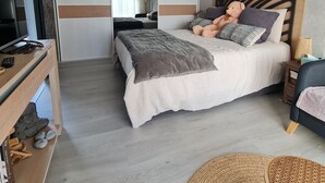 A bedroom with a bed, a television, a mirror, and a wooden headboard. - Nice little apartment (Pornic)