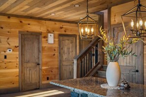 A wooden interior with a granite countertop, a vase with dried plants, and two hanging lantern-style lights. - 5-Bedroom Cabin with Indoor Pool, Pickleball Court & Hot Tub Near Dollywood (Sevierville)