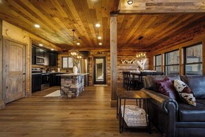 A spacious living area with a fireplace, a dining table, and a leather sofa. - 5-Bedroom Cabin with Indoor Pool, Pickleball Court & Hot Tub Near Dollywood (Sevierville)