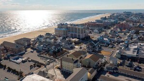 An aerial view of a coastal town with a beach, residential buildings, and a parking lot. - Newly Constructed Condo in the Heart of Ocean City (Ocean City)