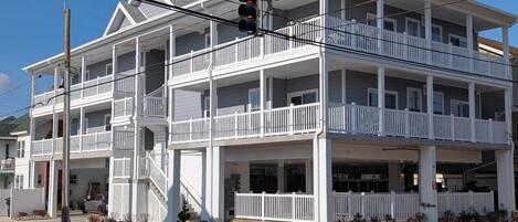 Un hotel de varios pisos con balcones, un hidrante y una señal de no estacionamiento.