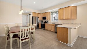 A modern kitchen with wooden cabinets, stainless steel appliances, and a marble countertop. - Downtown Condo Steps from the Beach and Boardwalk (Ocean City)