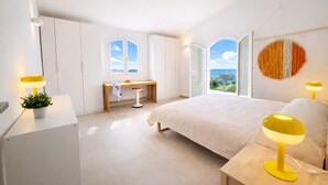 A bedroom with a bed, bedside lamps, a desk, and a view of the sea. - 🏡 Luxury Villa with Private Saltwater Pool – Porto ColumbuDiscover an exclusive oasis of luxury, privacy and relaxation in Porto Columbu, perfect for guests seeking a refined holiday in a modern and carefully designed villa.The property features a p (Sarroch)