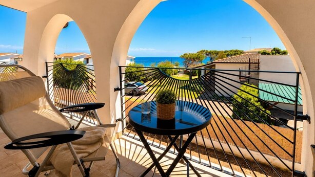 A balcony with a view of the sea, a chair, a small table, and a potted plant. - 🏡 Luxury Villa with Private Saltwater Pool – Porto ColumbuDiscover an exclusive oasis of luxury, privacy and relaxation in Porto Columbu, perfect for guests seeking a refined holiday in a modern and carefully designed villa.The property features a p (Sarroch)