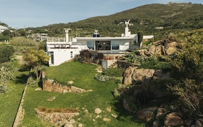Une maison moderne dotée d’une piscine, entourée d’un jardin et d’un terrain rocheux.