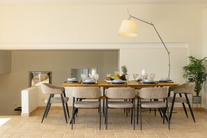 A dining area with a long table, six chairs, and a pendant light.