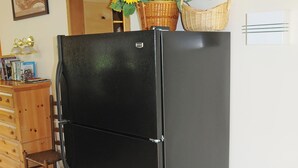 A black refrigerator in a room with wooden furniture, a wooden ceiling, and a wall-mounted picture.