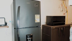 Eine kompakte Küchenzeile mit einem modernen, schwarzen Kühlschrank, einer eingebauten Mikrowelle und einem Wasserspender.