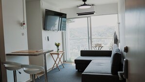 Ein modernes, minimalistisches Wohnzimmer mit einer Couch, einem kleinen Tisch und einem an der Wand befestigten Fernseher.
