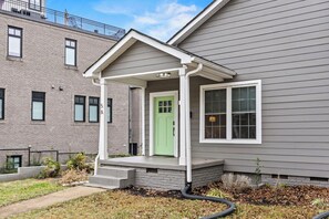 A two-story building with a green door and a covered porch. - Modern 1-Bed, Walk to Fluor Field and Downtown (Greenville)