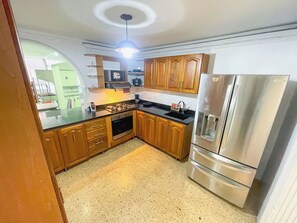 A kitchen with wooden cabinets, a stainless steel refrigerator, a microwave, and a stove.