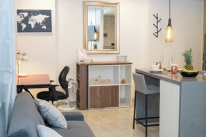 A modern living room with a grey sofa, a wooden cabinet with 'Amor' written on it, a small table with a pineapple, and a world map on the wall. - Staynova Acogedor Loft en El poblado (Medellín)