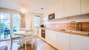 Una cocina moderna con armarios blancos, una encimera de madera y un microondas integrado.