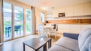 Una cocina moderna con armarios blancos, encimera de madera y microondas integrado.