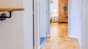 A hallway with wooden flooring, white walls, and a wooden door at the end. - Douceur de vivre près de la mer (Bénodet)