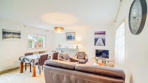 A modern living room with a brown leather sofa, a dining table with chairs, a television, and artwork on the walls. - Douceur de vivre près de la mer (Bénodet)