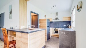 A modern kitchen with a wooden island, built-in oven, and a grey marble accent wall. - Douceur de vivre près de la mer (Bénodet)