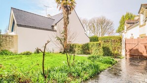 A modern house with a sloped roof, a well-maintained lawn, and a stone pathway leading to a wooden gate. - Douceur de vivre près de la mer (Bénodet)