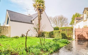 A modern house with a sloped roof, a well-maintained lawn, and a stone pathway leading to a wooden gate. - Douceur de vivre près de la mer (Bénodet)