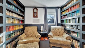 Una biblioteca con dos sillones estampados, una mesita y estanterías llenas de libros.