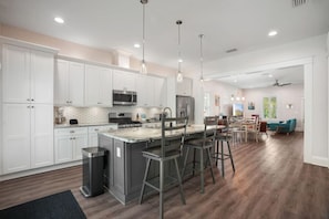A modern kitchen with white cabinets, stainless steel appliances, and a central island with bar stools.