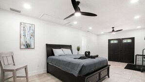 A bedroom with a bed, a chair, a ceiling fan, and a door. - Expansive Charm - 4BR Estate on Private Acre (Brandon)