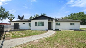 A single-story house with a front porch, a garage, and a small front yard. - Expansive Charm - 4BR Estate on Private Acre (Brandon)