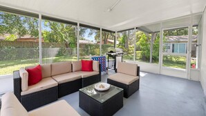 A covered patio with a sectional sofa, two armchairs, and a glass coffee table. - King-Style Retreat · 4 BR · Family Friendly (Tampa)