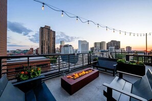 Une terrasse sur le toit dotée d’un foyer, d’un espace salon extérieur et offrant une vue panoramique sur la ville.