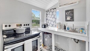 Una cocina con estufa, horno y un letrero de café en la pared.