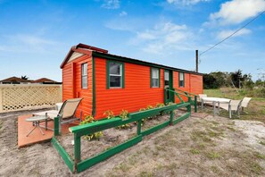 Eine rote Holzhütte mit einer grünen Veranda, einem Tisch und Stühlen.