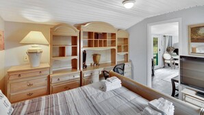 Un dormitorio con cama, mesita de noche, lámpara, cómoda y televisor.
