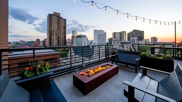 Une terrasse sur le toit dotée d’un foyer, d’un espace salon extérieur et offrant une vue panoramique sur la ville.