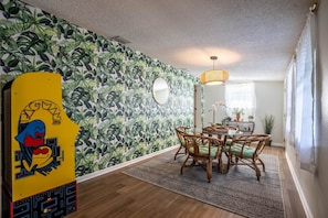 Un coin repas avec une table ronde, des chaises en osier et un tapis à motifs.