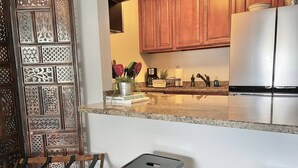 Una cucina con mobili in legno, un frigorifero in acciaio inossidabile e un piano di lavoro in granito.
