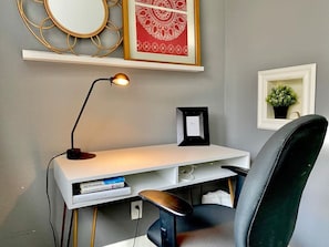 Un bureau moderne, doté d’une lampe, d’une chaise et d’une étagère ornée d’objets décoratifs.