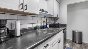 A modern kitchen with a black countertop, stainless steel sink, and white cabinets.