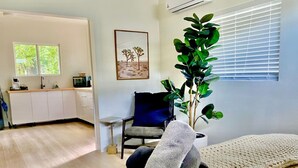 Une chambre à coucher avec un lit, une chaise, une plante et une fenêtre.