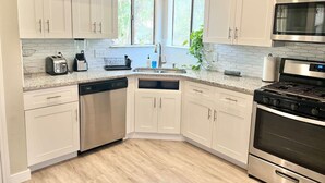 A modern kitchen with white cabinets, a dishwasher, a stove, and a microwave. - The Lovely. Perfect ATX Family Getaway (Austin)