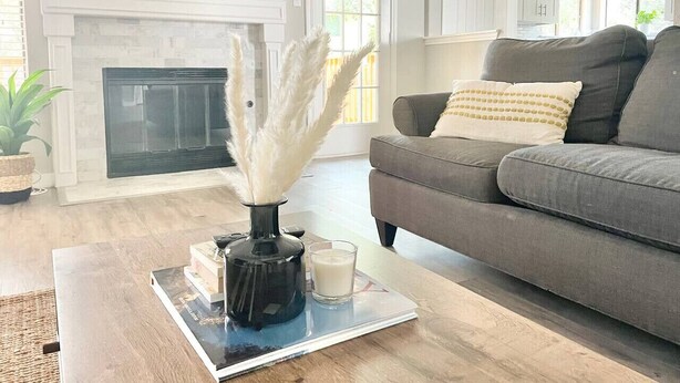 A living room with a fireplace, a grey sofa, and a coffee table with books and a vase. - The Lovely. Perfect ATX Family Getaway (Austin)