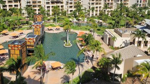 Ein Resort mit mehreren Hotelgebäuden, einem zentralen Pool und umliegenden Palmen.